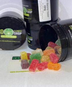 CBD Gummies in CD Flower Shop branded pots. The gummies are brightly coloured and spread across the surface.