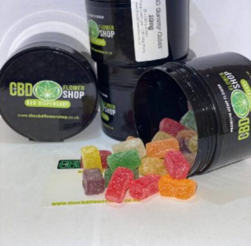CBD Gummies in CD Flower Shop branded pots. The gummies are brightly coloured and spread across the surface.