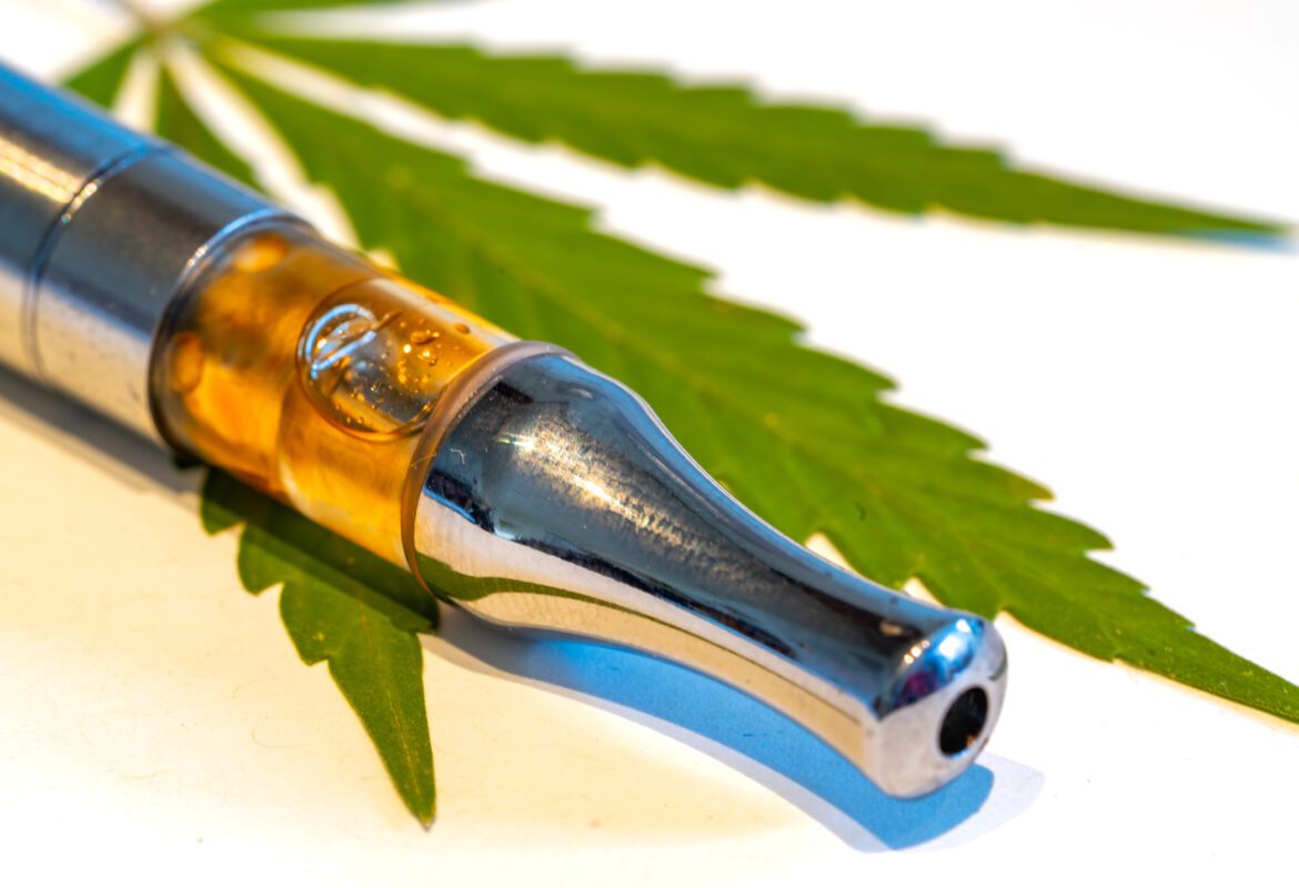 Close up of a CBD vape on a cannabis leaf.