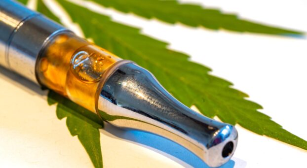 Close up of a CBD vape on a cannabis leaf.