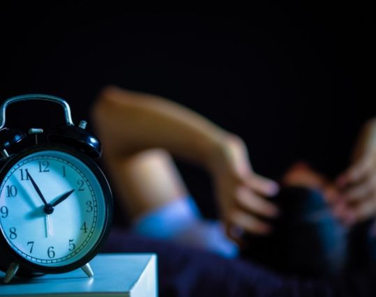 alarm clock with person sleeping in the background