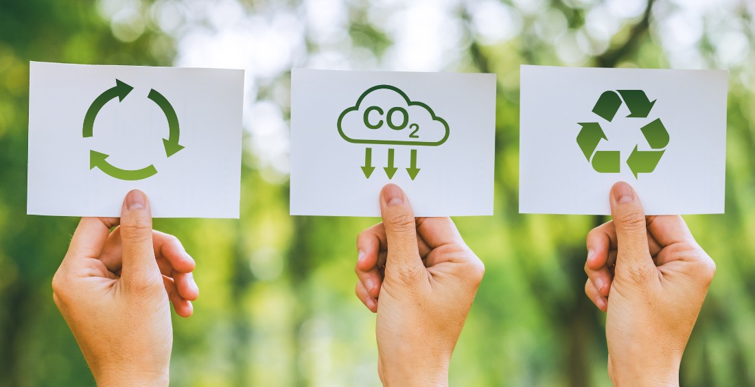 Three hands holding up cards with sustainability symbols