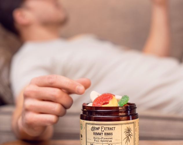 Man lying down reaching for CBD gummies