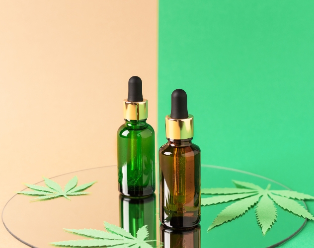 Two cbd oil dropper bottles on mirrored surface with coloured background