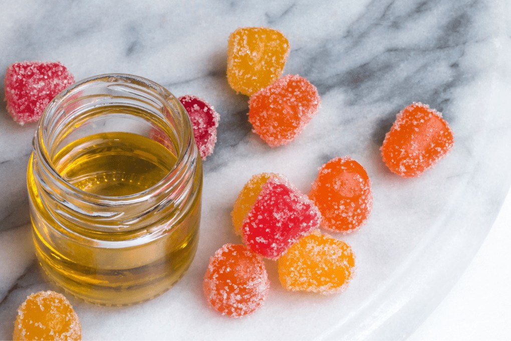 Jar of CBD oil and CBG gummies on marble surface