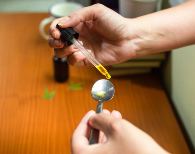 person putting CBD oil onto a teaspoon