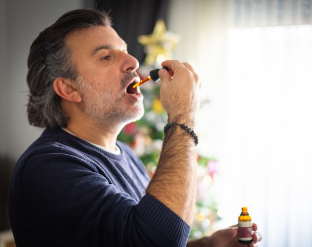 man taking CBD oil under the tongue