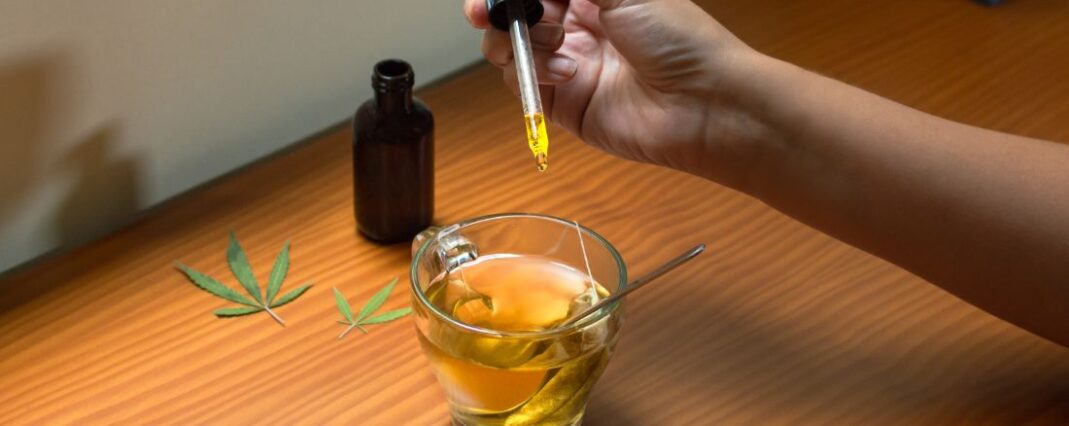 person dropping cbd oil into cbd tea with pipette