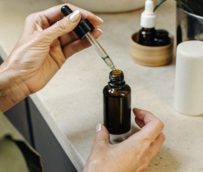 a woman opening a CBD oil bottle on a counter