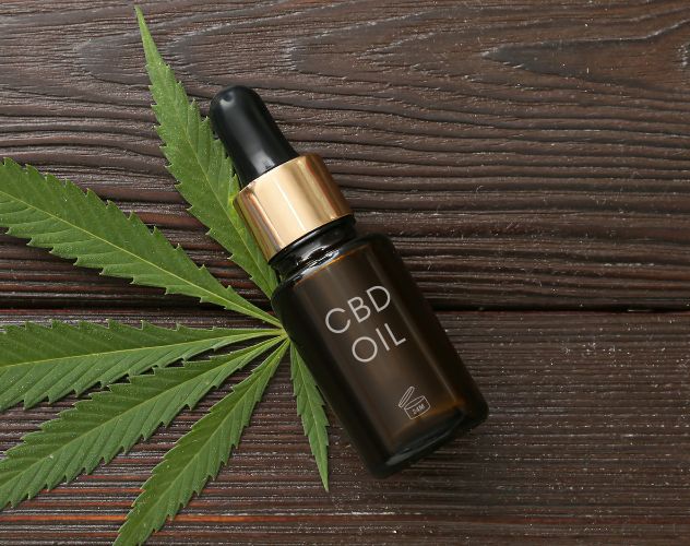 cbd oil dropper bottle on top of hemp plant leaf labelled with 24 months shelf life