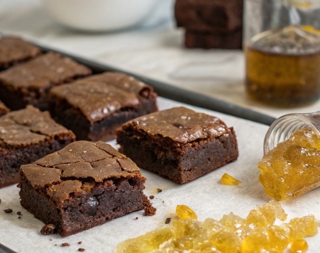 chocolate brownies on a board with a spilled pot of cbd wax
