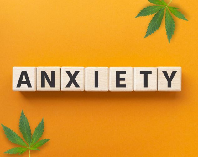 Anxiety letters on square blocks on an orange background with hemp leaves