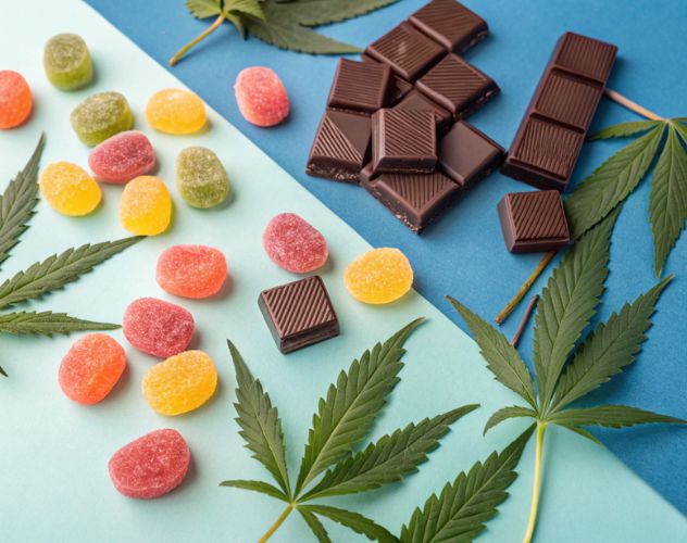 gummy sweets and chocolate bar pieces on a blue coloured background with hemp leaves