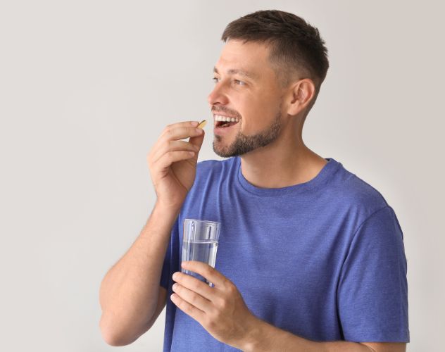 man taking a cbd oil capsule with a glass of water