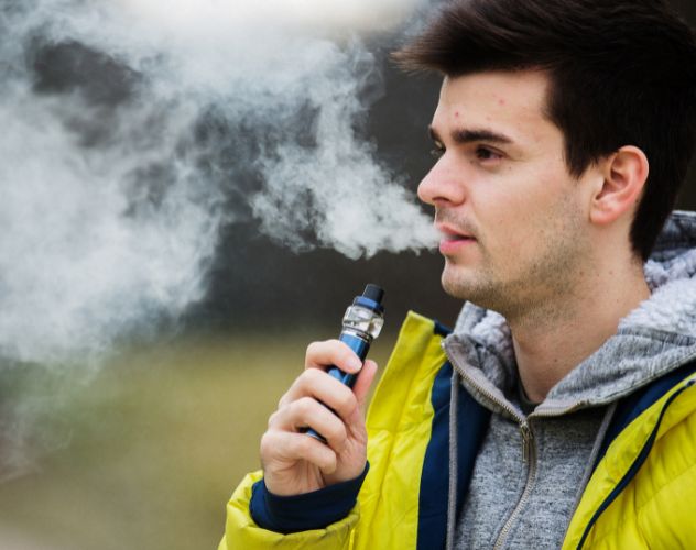 man in a yellow coat vaping 