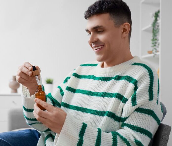 man smiling opening a bottle of cbd oil