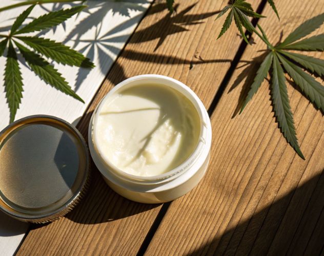 open pot of cbd lotion with shadows of hemp plants