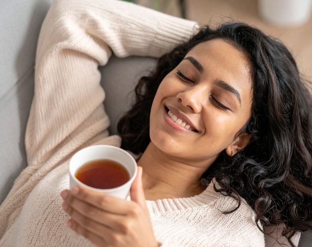 woman laying down with a cup of tea
