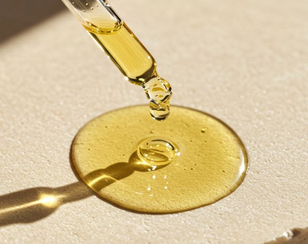 face serum oil dropping from an oil dropper onto a surface