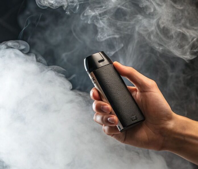 hand holding a black vape pod in a cloud of white smoke