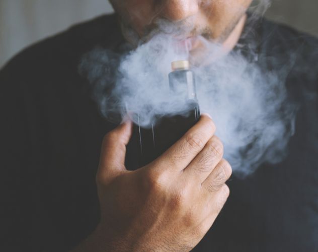 man vaping with a cloud of smoke coming out his mouth