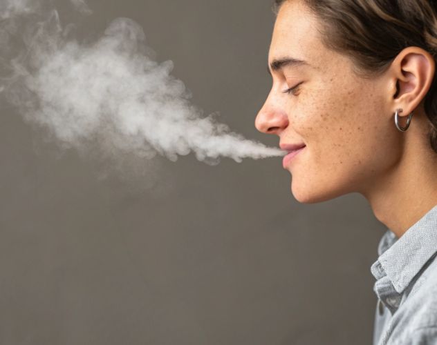 side profile of person blowing out vape smoke