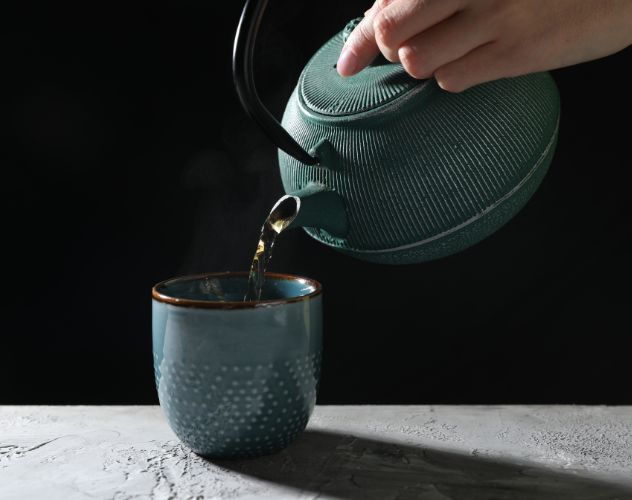 pouring tea from a teapot into a mug