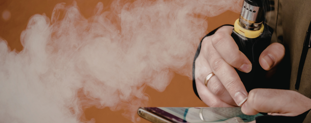 person holding a vape while texting