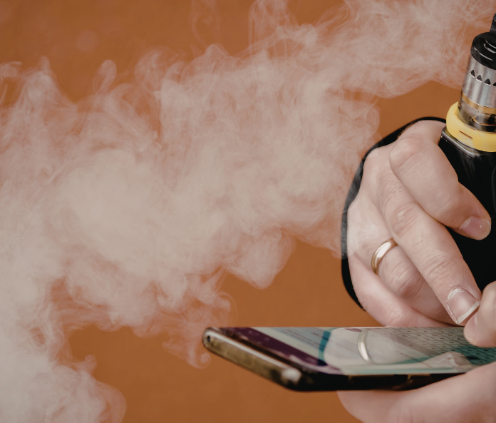 person holding a vape while texting