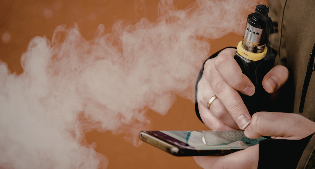 person holding a vape while texting