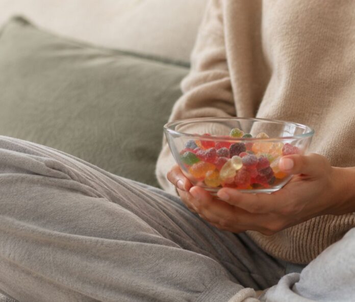 woman holding a bowl of gummies on the sofa