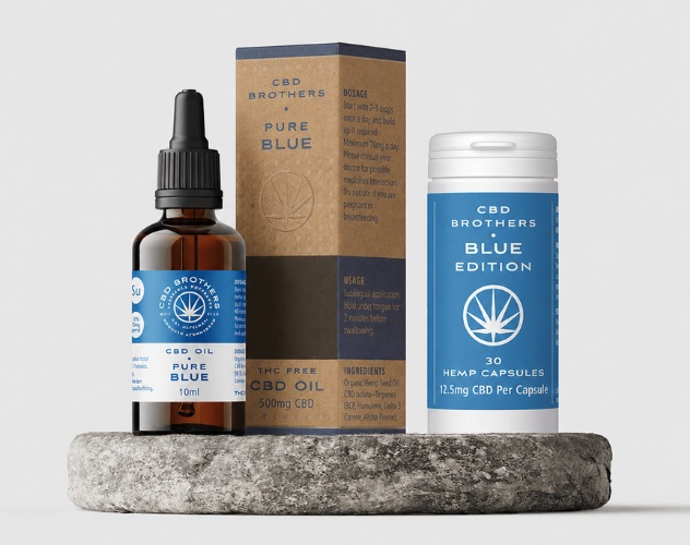 CBD brothers blue edition capsules and oil on a round stone plinth
