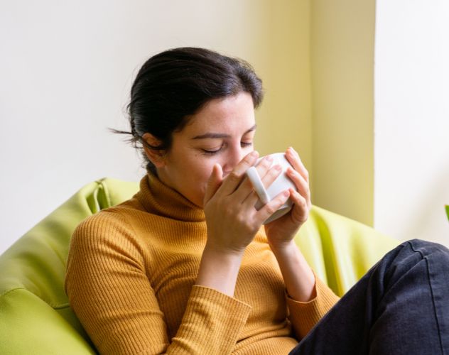 woman drinking a cup of tea sitting on a beanbag